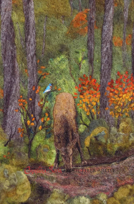 artwork wool painting of a deep forest scene of a female elk drinking from a pond or stream. Some trees have bright red and orange foliage. There is a carolina bluebird perched on a branch next to the elk.