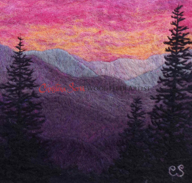 artwork painting made of wool of a colorful red and orange sunset over purple mountains with black pine tree silhouettes in the foreground. 